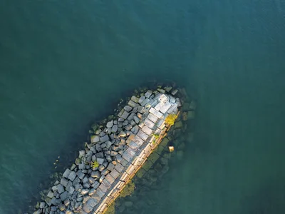 Aerial shot of a rock pier extending into calm blue water in Ashtabula, Ohio.