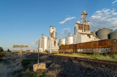 Grain silos and vintage Rio Grande train cars under a wide blue sky on the Colorado Eastern Plains.