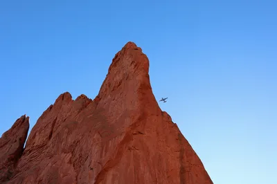 A small airplane flying past the iconic red sandstone rock formations of Garden of the Gods in Colorado Springs.