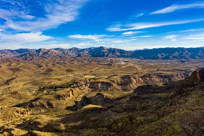 Aerial view of rugged desert mountains under a vast blue sky in Arizona