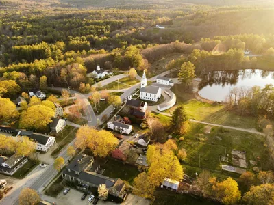 Aerial view of Hancock, New Hampshire during fall foliage with a church and lake