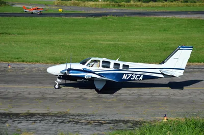 A light twin-engine aircraft and a single-engine trainer taxiing on a paved airport runway under clear skies.